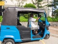 The elderly driver of three-wheeled taxi waiting for passenger during the sunny day.