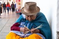 An elderly ecuadorian woman weaves a straw basket