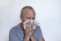 An elderly European man blows his nose, sneezes and coughs into a napkin. Coronavirus infection