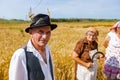 Elderly farmer poses in traditional suit. Wheat harvest time