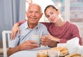 Elderly father and adult daughter talk and drink tea in the kitchen