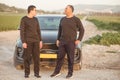 Elderly father and young son standing next to car in nature on road trip. Royalty Free Stock Photo