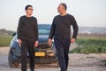 Elderly father and young son standing next to car in nature on road trip. Royalty Free Stock Photo