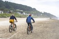 An elderly father and a young son travel side by side on bicycles along the Pacific Ocean preferring an active healthy lifestyle Royalty Free Stock Photo