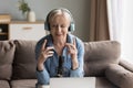 Elderly female blogger wear headphones speaking into professional microphone Royalty Free Stock Photo