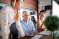 An elderly female boss is having a conversation with her female colleagues about a work they are doing together at workplace. Royalty Free Stock Photo