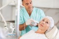 Elderly female client receiving hardware ultrasonic to revitalize and tighten facial skin at cosmetology clinic Royalty Free Stock Photo