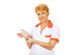 Elderly female doctor or nurse holds pink breast cancer awareness ribbon Royalty Free Stock Photo