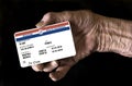 An elderly female hand holds a mock United State government Medicare Health Insurance card. It is a generic card. Royalty Free Stock Photo