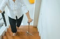 Elderly woman holding sticks while walking up stair at home