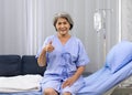 Elderly female patient raise finger thumbs up with a smile while sitting on the bed in the hospital ward Royalty Free Stock Photo