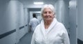 Elderly female patient stands in clinic corridor, looks at camera Royalty Free Stock Photo