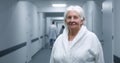 Elderly female patient stands in clinic corridor, looks at camera Royalty Free Stock Photo