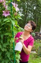 Elderly female taking care of plants, spraying a plant with pure water from a bottle Royalty Free Stock Photo