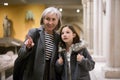 Elderly female tutor showing tween girl ancient sculptures in museum