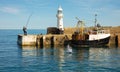 An elderly fisherman catches a large fish at the Falmouth harbor entrance. Royalty Free Stock Photo