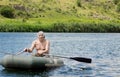 Elderly fisherman rowing across a lake