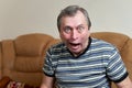 Elderly freak making faces while sitting on the couch looking at the camera