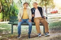Elderly friends, happy and men on park bench, talking and bonding outdoor to relax in retirement. Funny senior people Royalty Free Stock Photo