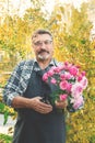 Elderly gardener with a bouquet of roses. elderly man with a beard holds a bouquet of pink roses cut in the garden