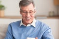 Elderly Gentleman Holding Cellphone Reading Message Sitting On Couch Indoor Royalty Free Stock Photo