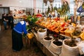 Elderly Georgian Woman Seller Sorting Herbs Near Abundant Counte