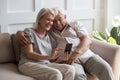 Elderly grandfather and grandmother spend time having fun using smartphone
