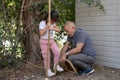 Grandfather Teaching His 7-Year-Old Granddaughter to Climb a Rope in the Park.