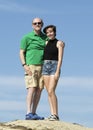 Elderly grandfather and teenage granddaughter standing on a rock