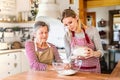 An elderly grandmother with an adult granddaughter at home, baking.