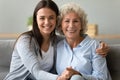 Elderly grandmother adult granddaughter sitting on couch posing for camera