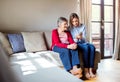 Elderly grandmother and adult granddaughter with smartphone at home. Royalty Free Stock Photo