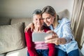 Elderly grandmother and adult granddaughter with smartphone at home. Royalty Free Stock Photo