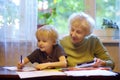 Elderly grandmother helping little grandchild doing homework. Grandma and grandson