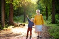 Elderly grandmother and her little grandchild walking together in sunny summer park. Grandma and grandson