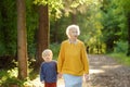 Elderly grandmother and her little grandchild walking together in sunny summer park. Grandma and grandson Royalty Free Stock Photo