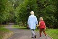 Elderly grandmother and her little grandchild walking together in sunny summer park. Grandma and grandson. Two generations of Royalty Free Stock Photo