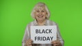 Elderly grandmother holding Black Friday text inscription banner. Senior woman rejoicing discounts