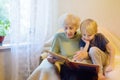 Elderly grandmother and little grandchild looking family photos album. Grandma and grandson Royalty Free Stock Photo