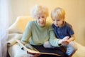 Elderly grandmother and little grandchild looking family photos album. Grandma and grandson Royalty Free Stock Photo