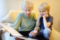 Elderly grandmother and little grandchild looking family photos album. Grandma and grandson Royalty Free Stock Photo