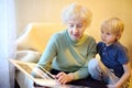 Elderly grandmother and little grandchild looking family photos album. Grandma and grandson Royalty Free Stock Photo