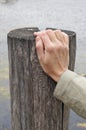 The elderly grandmother rests his right hand on a wooden pillar