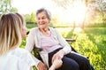 Elderly grandmother in wheelchair with granddaughter in spring nature.