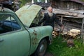 Elderly gray-bearded farmer standing near light green vintage c