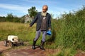 Elderly, gray-bearded man peasant farmer pulls cart with canister