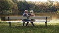Elderly gray haired couple siting on the bench near the river on autumn day. Romance and old age Royalty Free Stock Photo