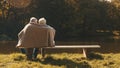 Elderly gray haired couple siting on the bench near the river covering with blanket on autumn day. Romance and old age