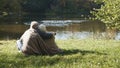 Elderly gray haired couple siting near the river covering with blanket on autumn day. Romance and old age Royalty Free Stock Photo