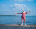 Elderly gray-haired man with a beard in a striped bathing suit and hat posing on the beach. Senior citizen on vacation Royalty Free Stock Photo